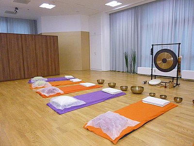 aufgereihte Yogamatten vor Klangschalen und einem Tamtam Gong